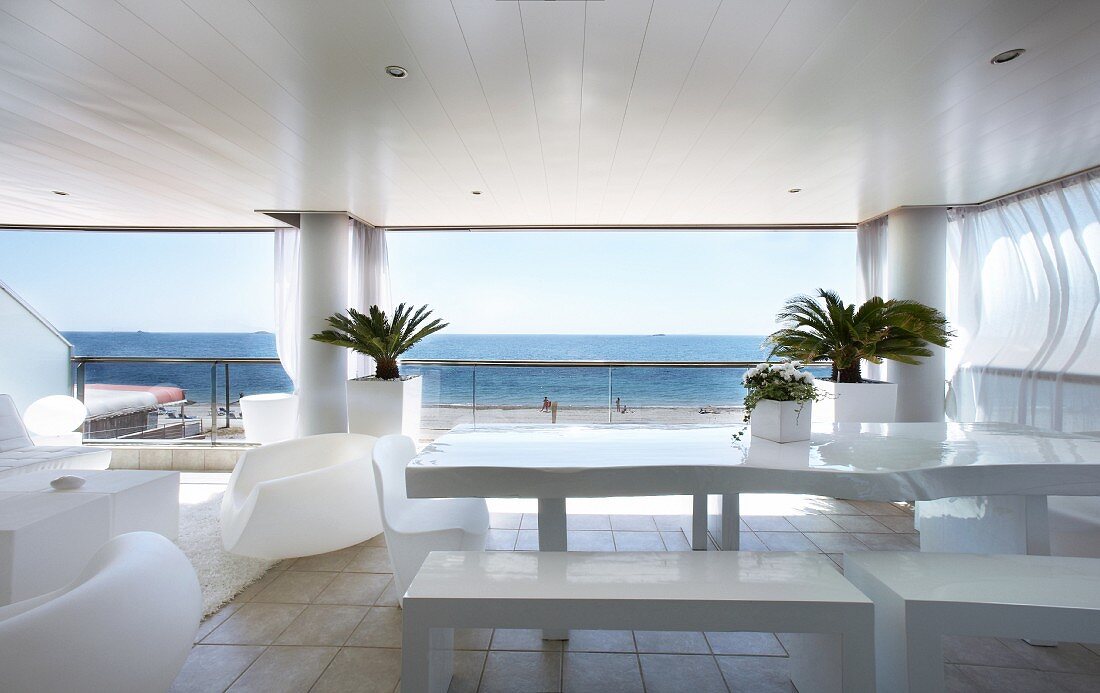 Spacious roofed terrace with white designer outdoor furniture and panoramic sea view