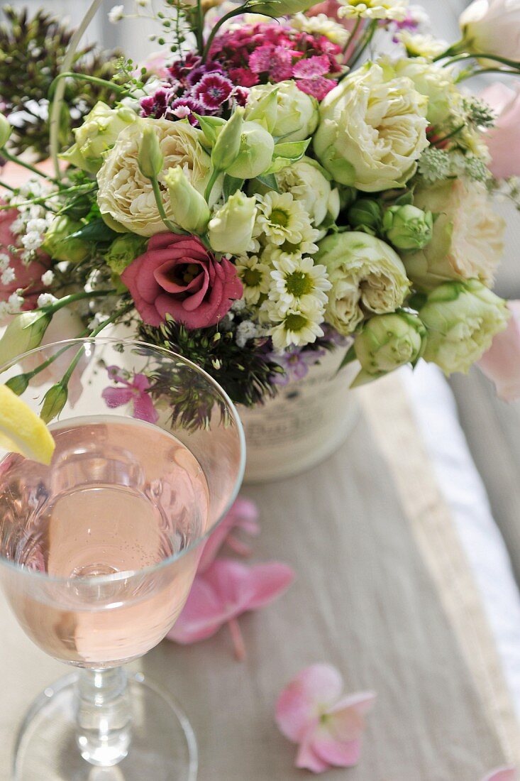Festlicher Blumenstrauss und Erfrischungsgetränk auf Tisch