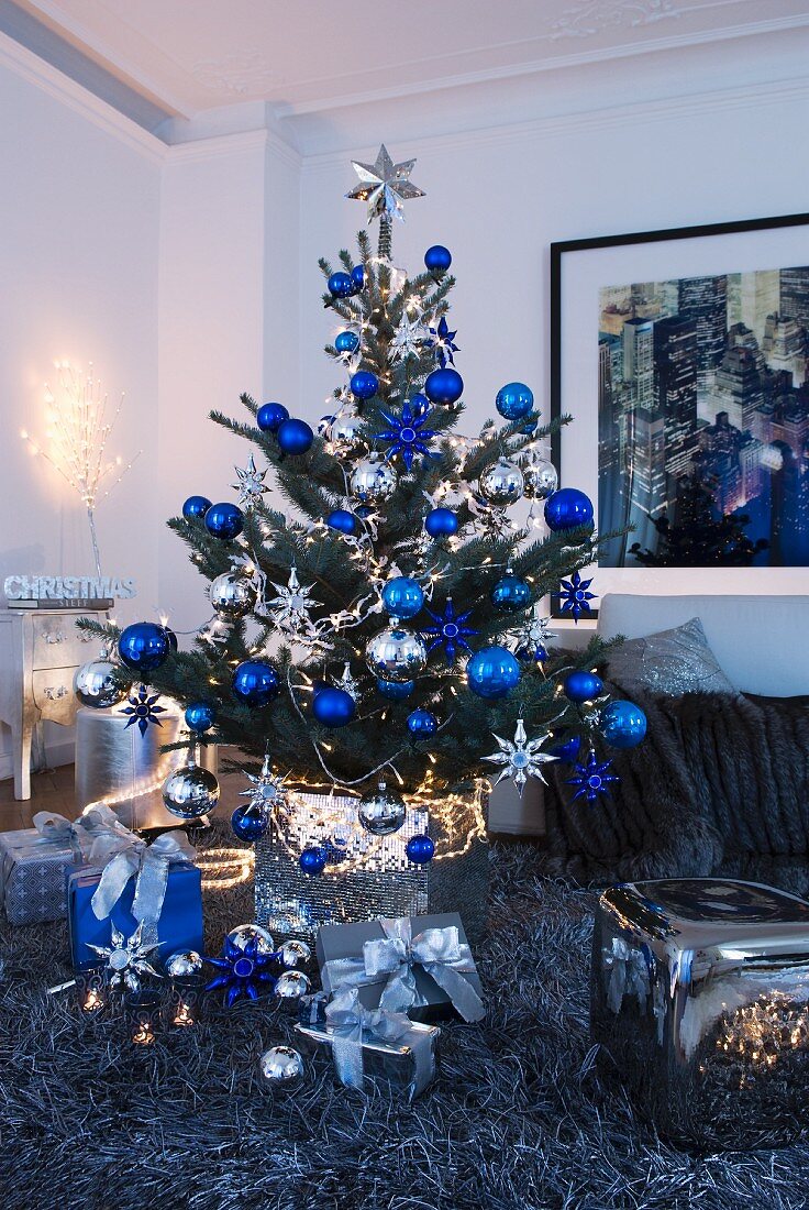 Weihnachtsbaum mit blauen und silbernen Kugeln auf flokatiähnlichem Teppich in Wohnzimmerecke