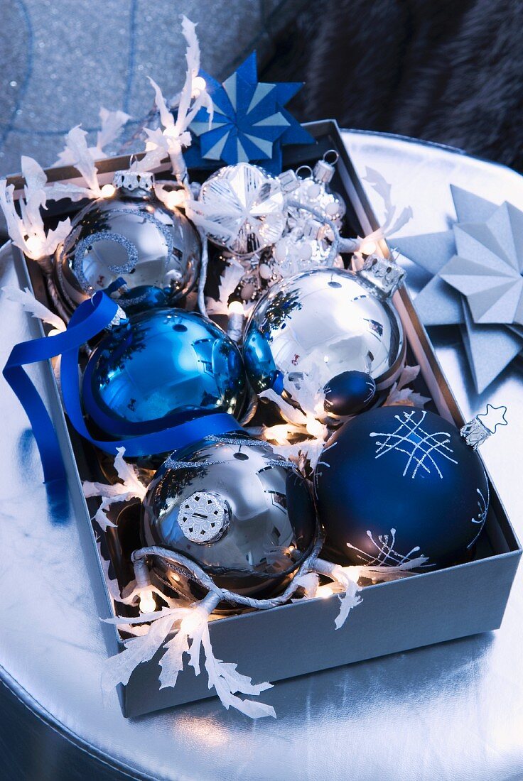 Decorated Christmas baubles and fairy lights in open box on table