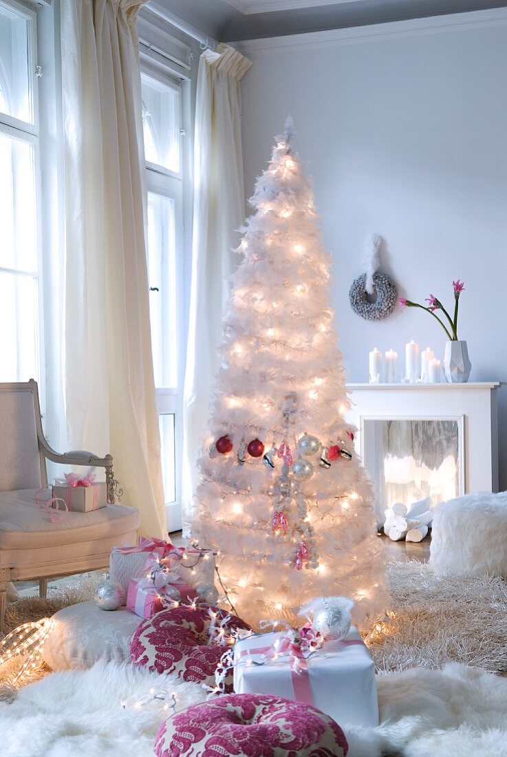 Weihnachtsbescherung - Künstlicher Weihnachtsbaum aus weissen Federn mit Beleuchtung und Geschenke auf Flokatiteppich in Wohnraum mit traditionellem Flair
