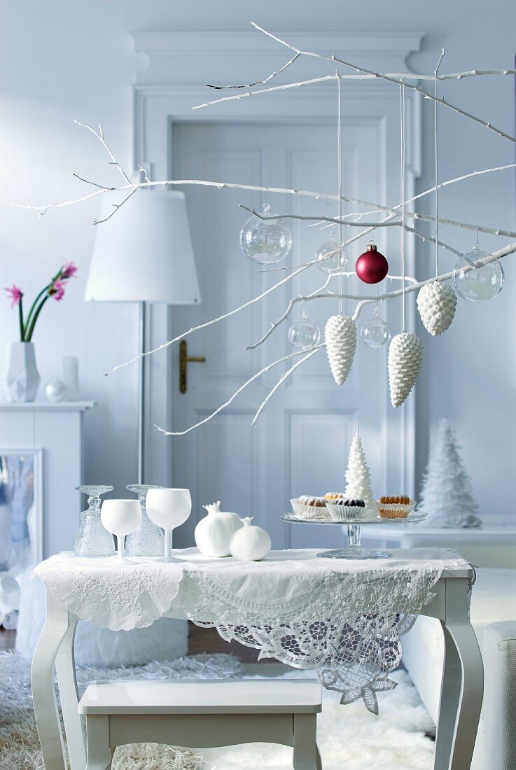 Christmas arrangement of twigs above side table with collection of white glass ornaments