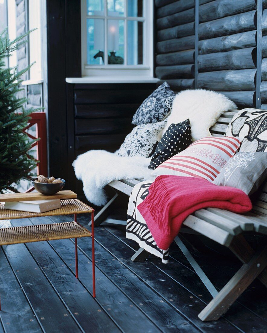 Schaffelle, Kissen und Decken auf einer Holzbank auf der Terrasse
