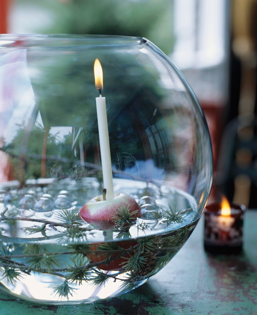 Lerchenzweige, Apfel und Kerze in einer Glaskugel