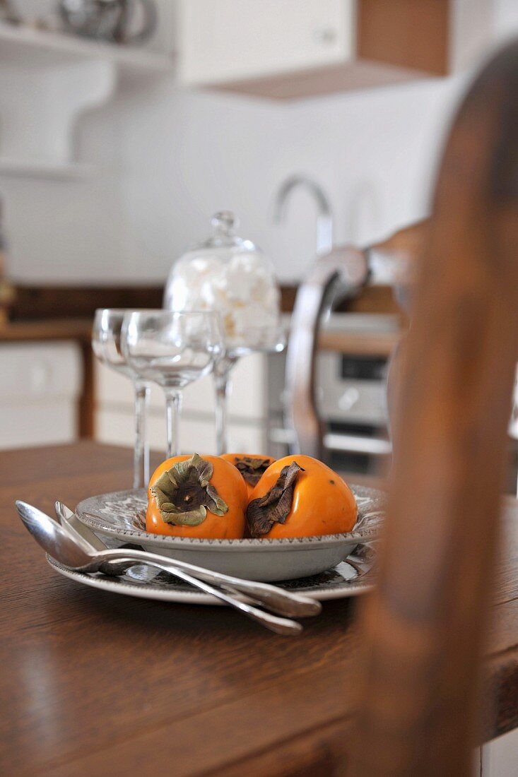 Place setting with persimmons on wooden table