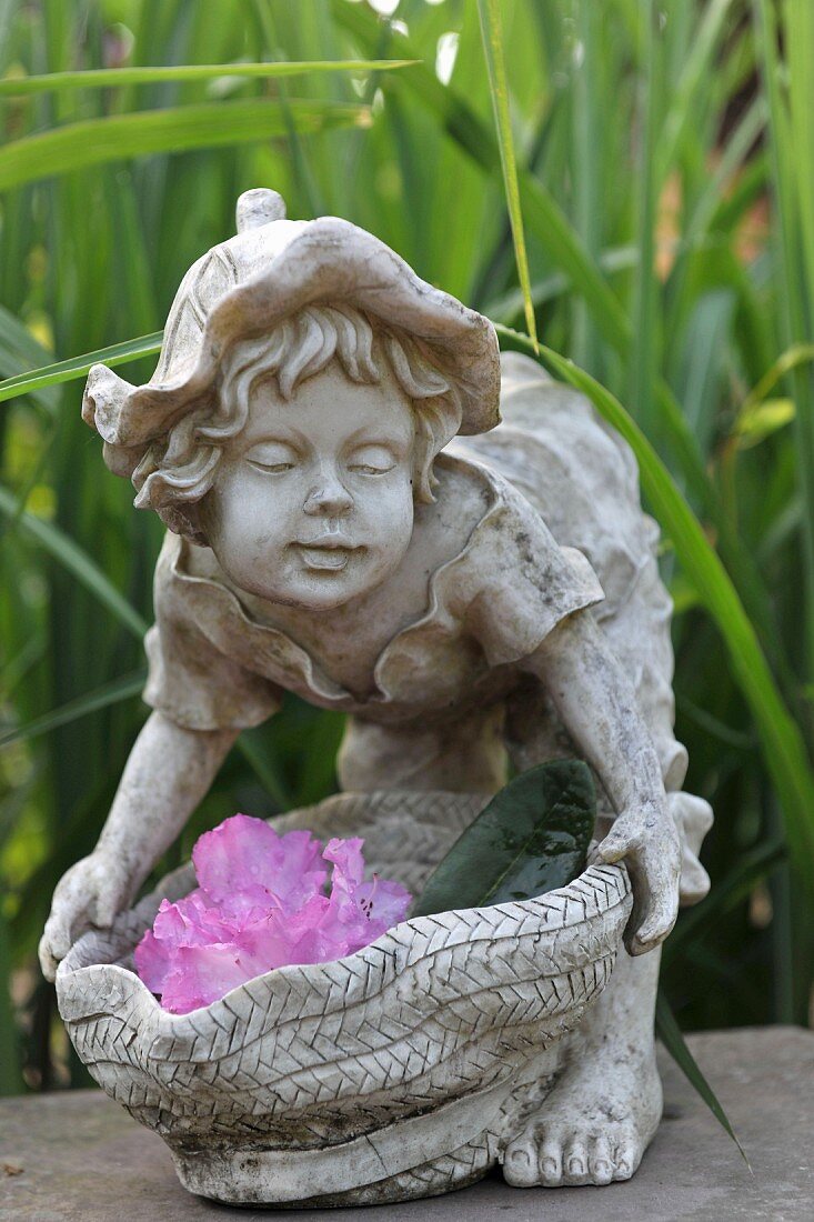 Kinderfigur aus Stein mit Blüten dekoriert