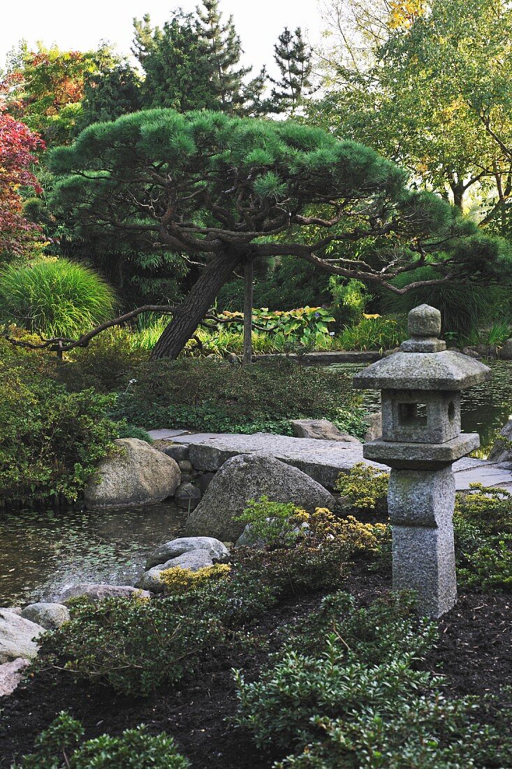 Asiatischer Garten mit japanischer Steinlaterne (Toro) neben Bachlauf