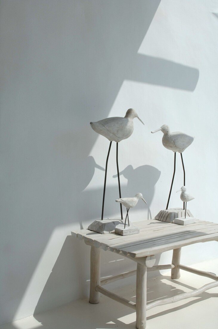 Modern bird-shaped figurines on rustic wooden stool