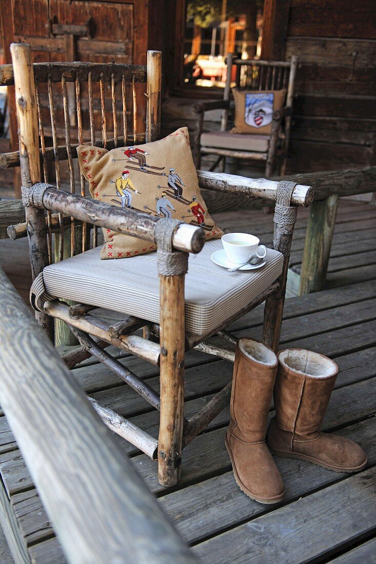 Selbstgebauter Stuhl mit Polster und Winterstiefel auf Holzveranda
