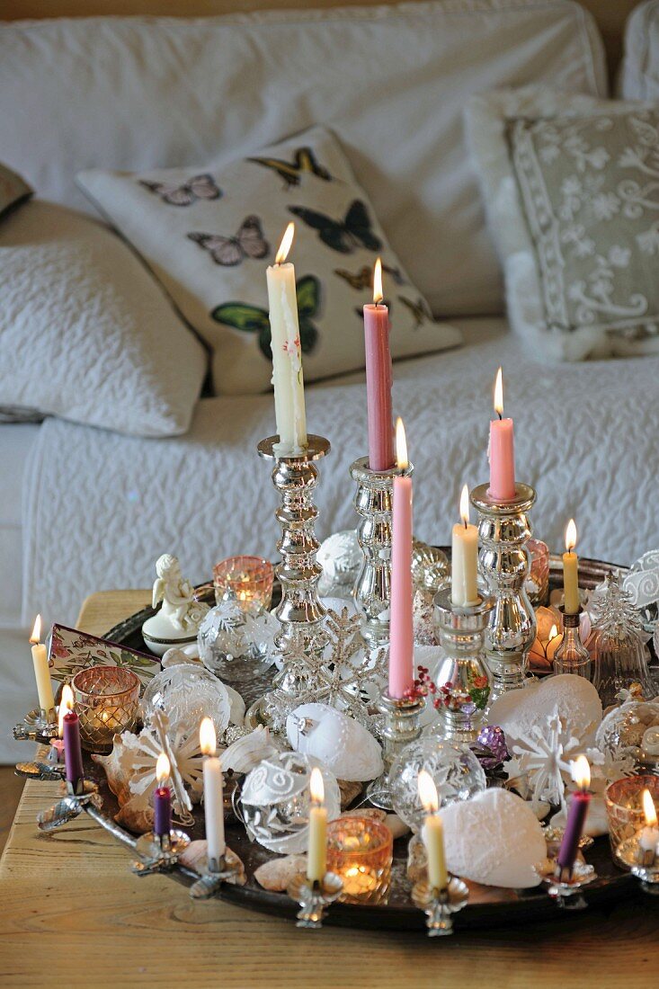 Festlich dekoriertes Tablett mit brennenden Kerzen und Weihnachtsschmuck auf Couchtisch