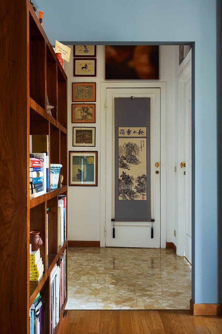 Seitliches Raumteilerregal und offener Durchgang zur Diele mit Blick auf Bildergalerie und japanischen Wandbehang an Zimmertür