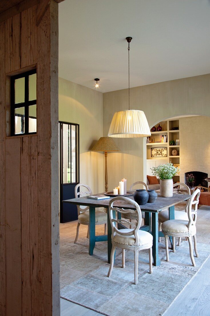 Blick durch offene Tür auf rustikalen Esstisch und Rokoko Stühlen vor breitem Durchgang