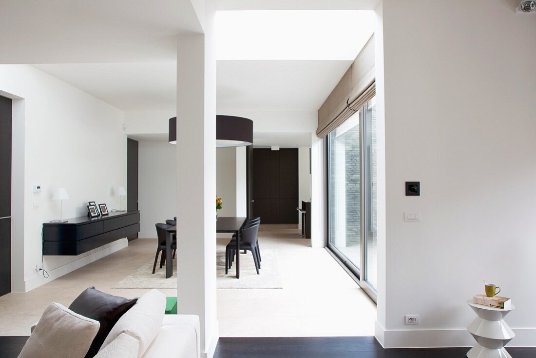 Blick in offenen Designer Wohnraum mit Essplatz in Schwarz und gehängtem Sideboard an Wand