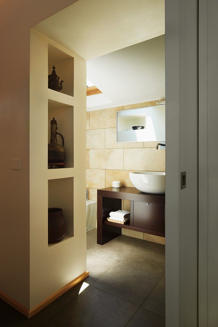 Blick in modernes Bad auf Waschtisch und Regalöffnungen in Wand