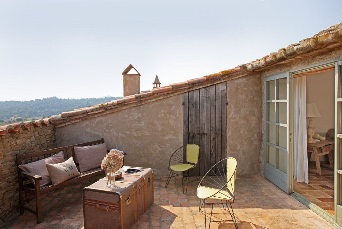 Fifties-style wire armchairs and travelling trunk used as table on Mediterranean roof terrace