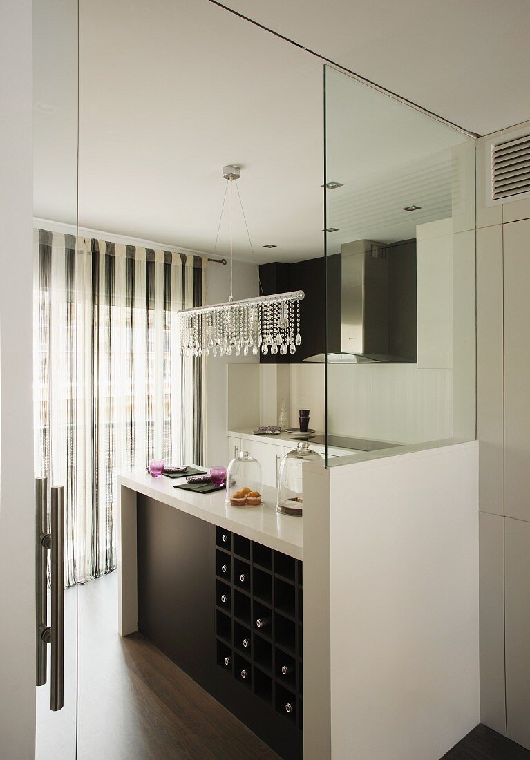 View through open door into black and white designer kitchen with pendant lamp decorated with glass beads