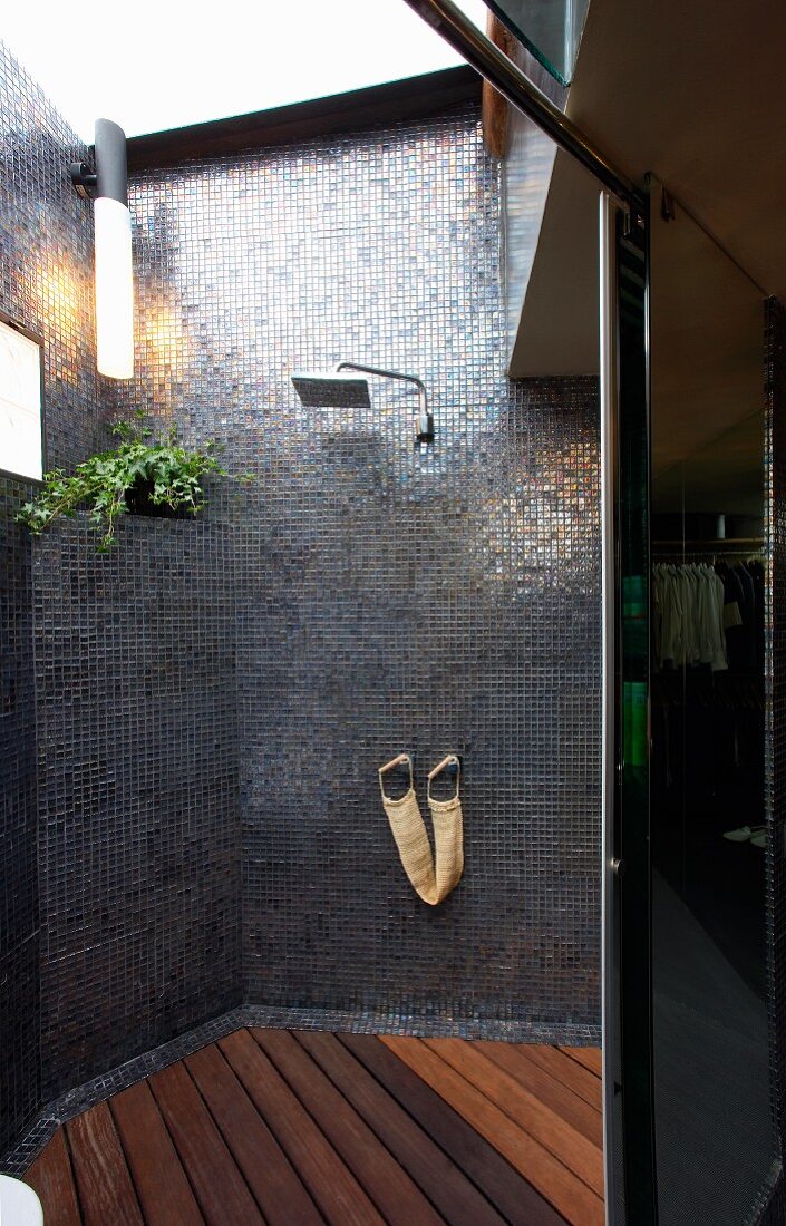 Modern shower with grey mosaic wall tiles and grid of wooden boards on floor