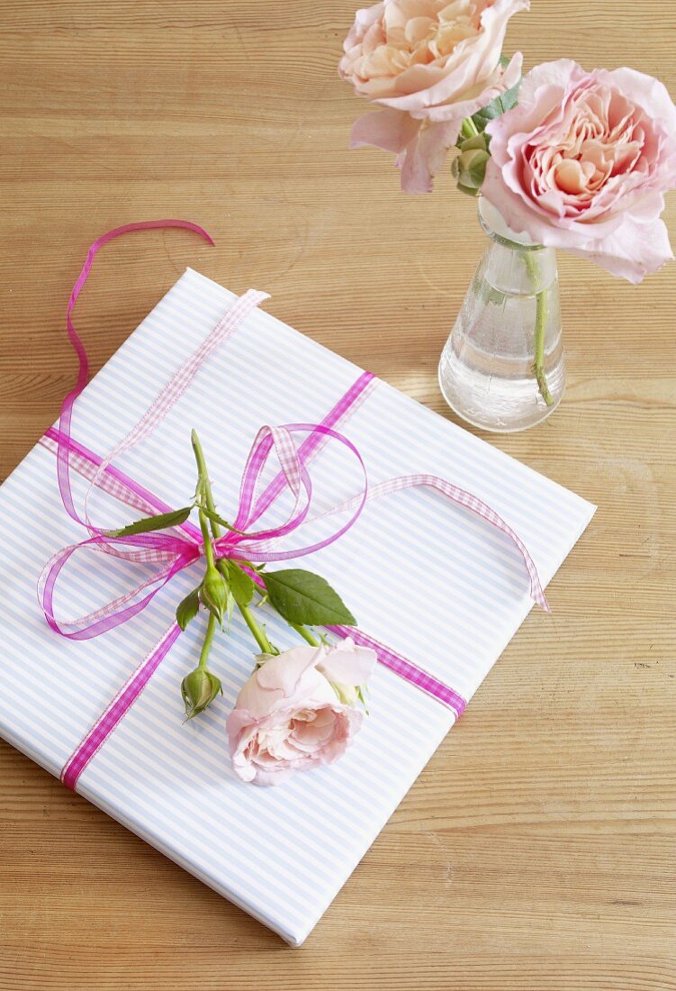 Verpacktes Geschenk mit Rosenblüten
