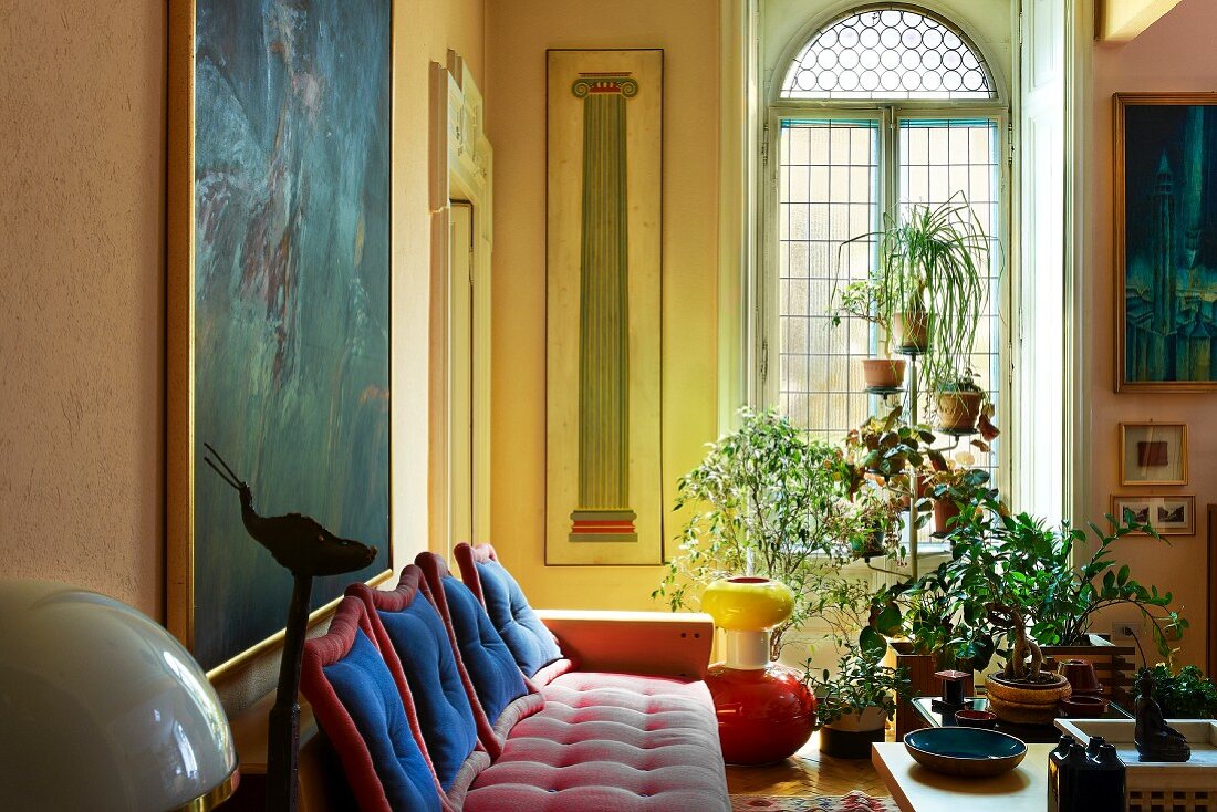Grand interior with red upholstered sofa and étagère in front of arched window