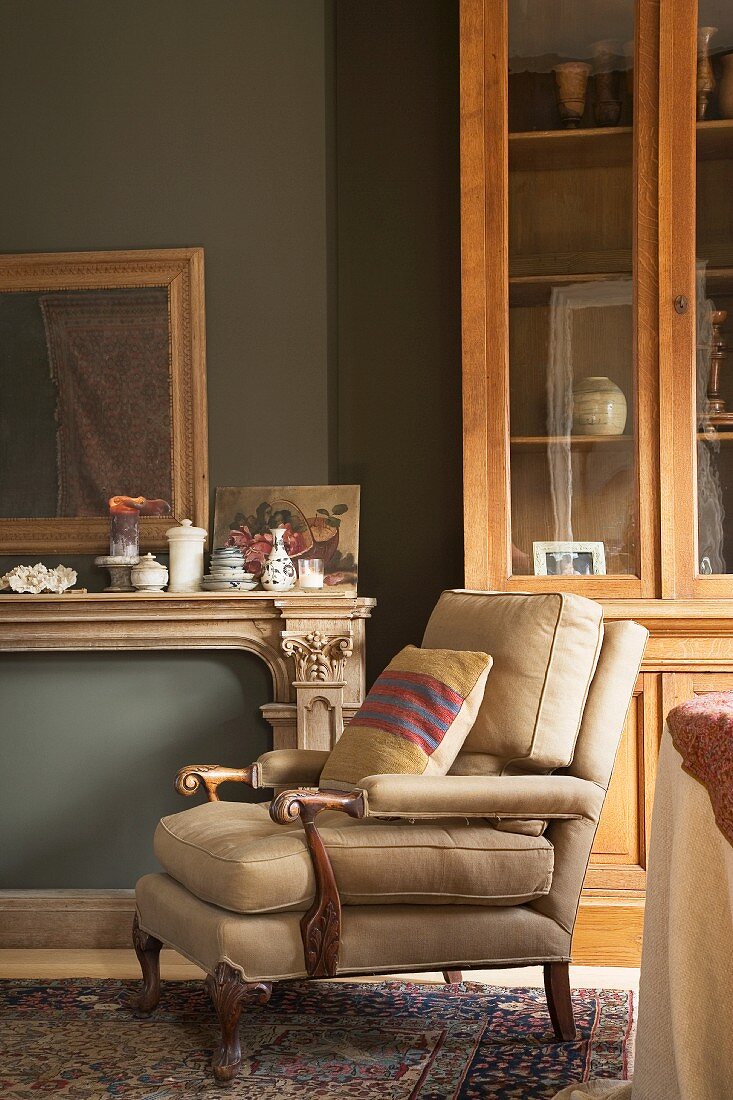 Armchair with antique wooden frame and new beige upholstery in renovated period apartment