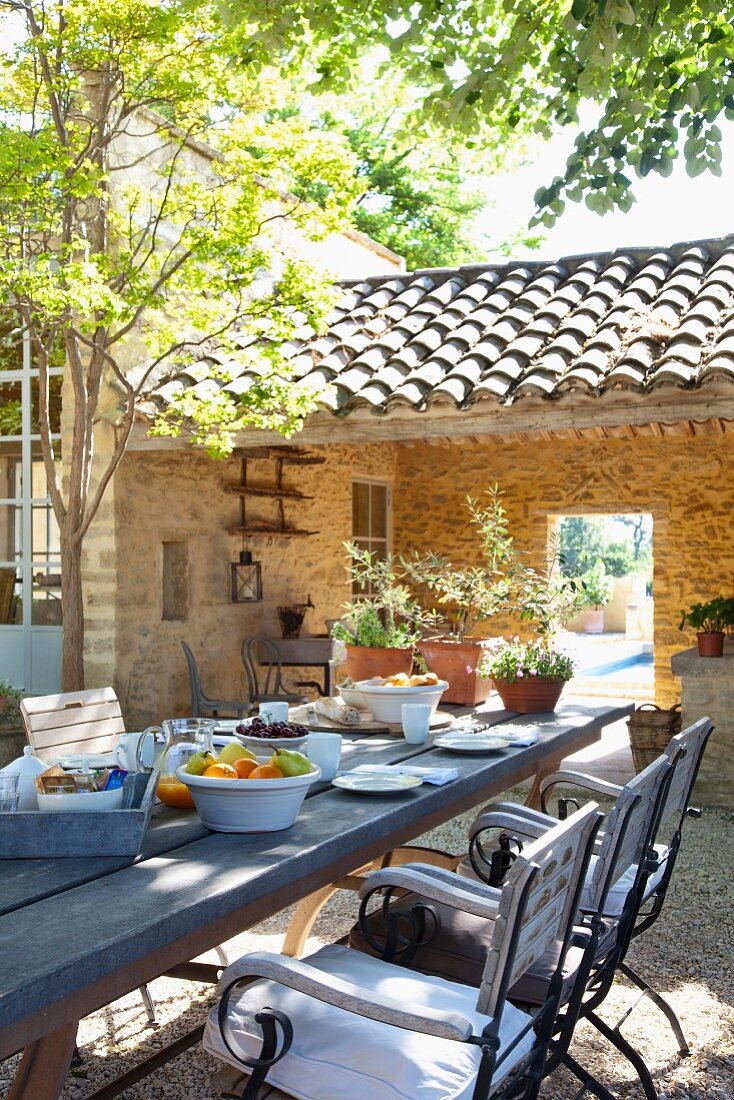 Langer Frühstückstisch in sonnigem Innenhof eines mediterranen Landhauses