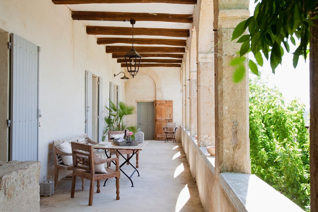 Antiker Stuhl und Tisch auf Veranda mit Arkaden eines mediterranen Landhauses