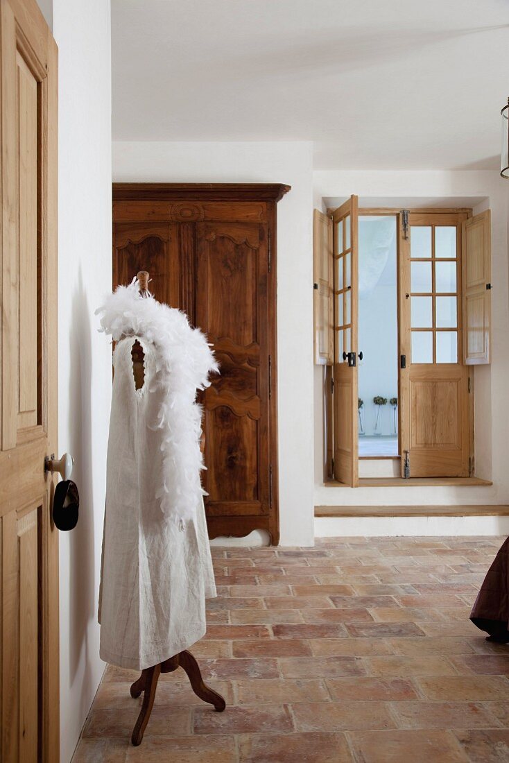 Tailors' dummy wearing white dress and feather boa on terracotta floor in foyer of old Mediterranean house