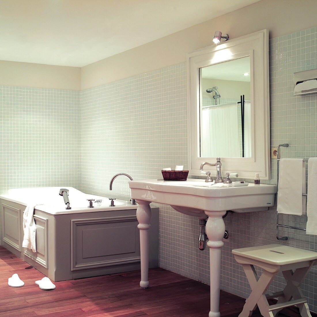 Vintage Bad: Waschtisch mit Keramikfüßen neben holzverkleideter Badewanne an Wand mit Mosaikfliesen