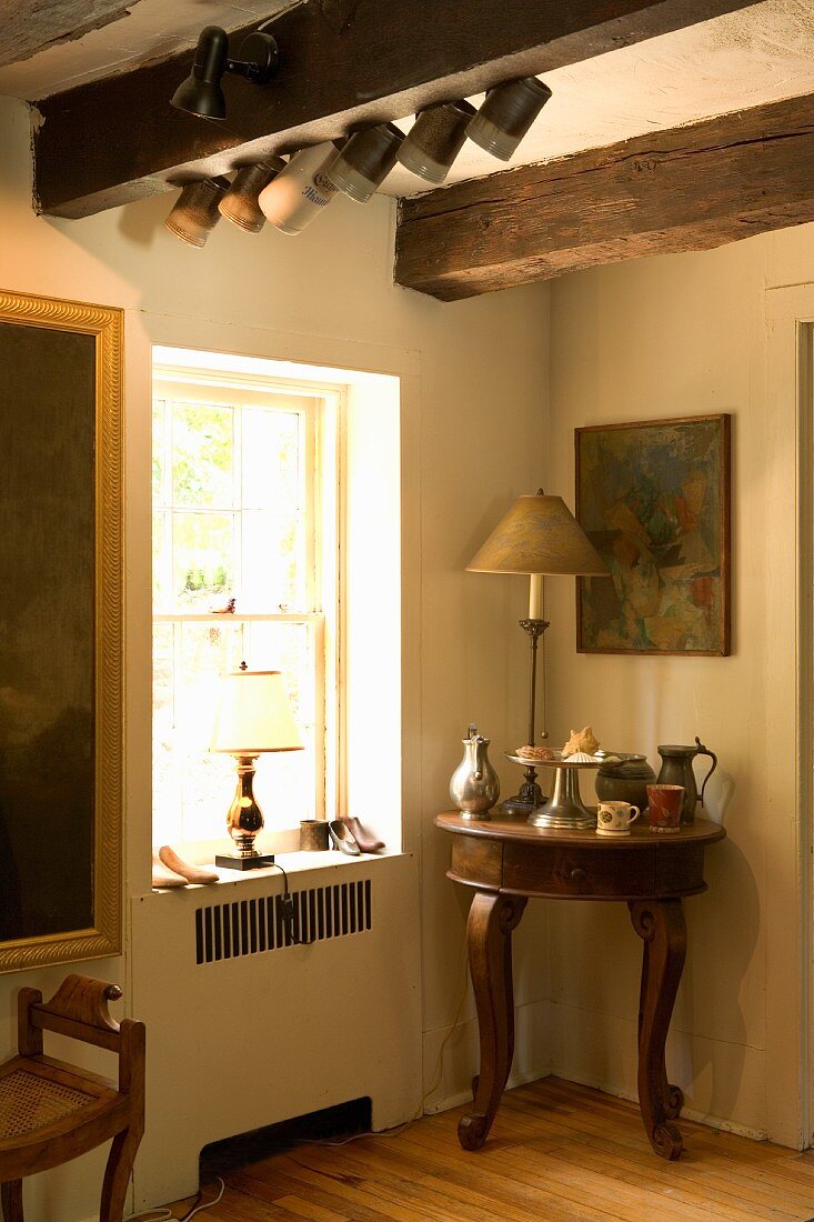 Krüge und Kannen auf antikem Beistelltisch in Zimmerecke neben Fenster