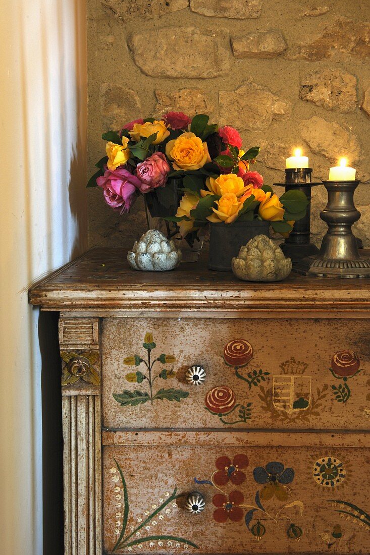 Blumenstrauß und Kerzen auf einer Kommode