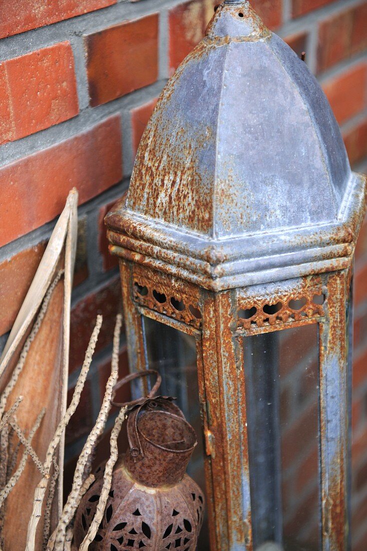 Rusty lantern in front of brick wall