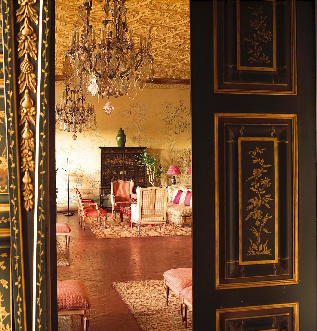 Offene Flügeltür in Schwarz mit goldenen Einlegearbeiten und Blick in herrschaftlichen Salon mit asiatischem Flair