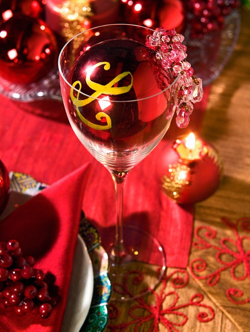 Gedeck und Weinglas mit roter Weihnachtsdeko