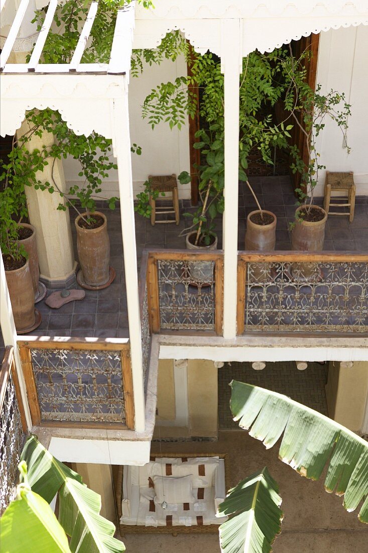 Potted trees on pergola balcony of Mediterranean house and view of courtyard below