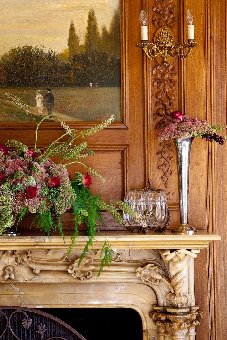 Vase of flowers and flower arrangement on carved mantelpiece against wooden wall with integrated painting