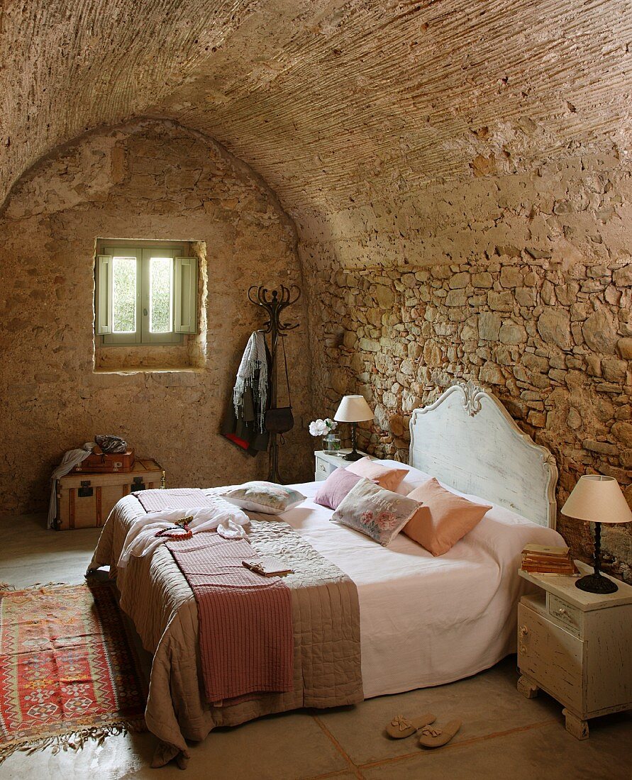 Doppelbett mit Kopfteil an Natursteinwand im Schlafzimmer mit Tonnendecke