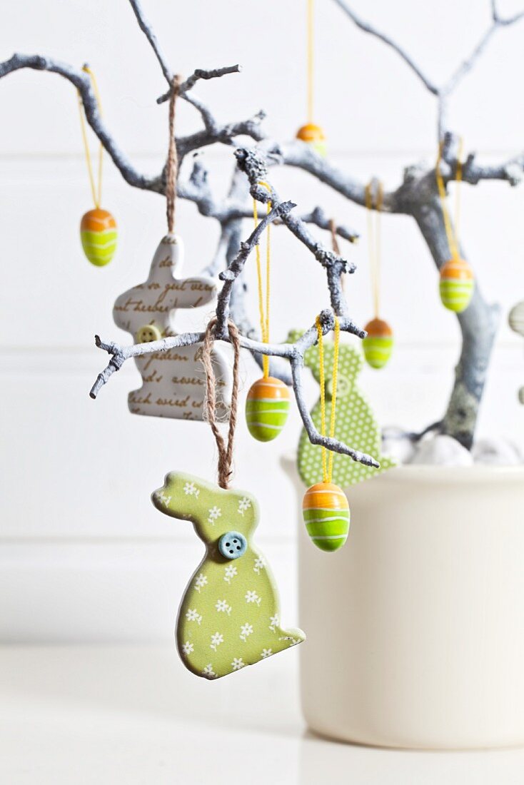 Easter arrangement with rabbits and eggs hanging from branch