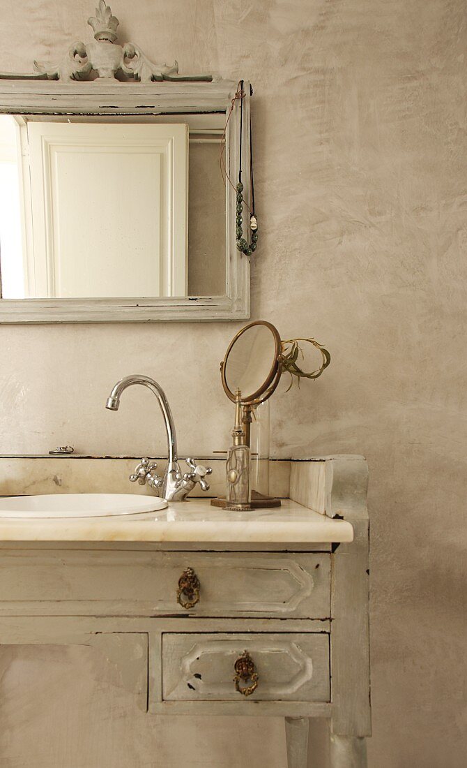 Originelles Vintage-Bad mit verziertem Spiegelrahmen und altem Schminktisch als Einbaumöbel für das Waschbecken