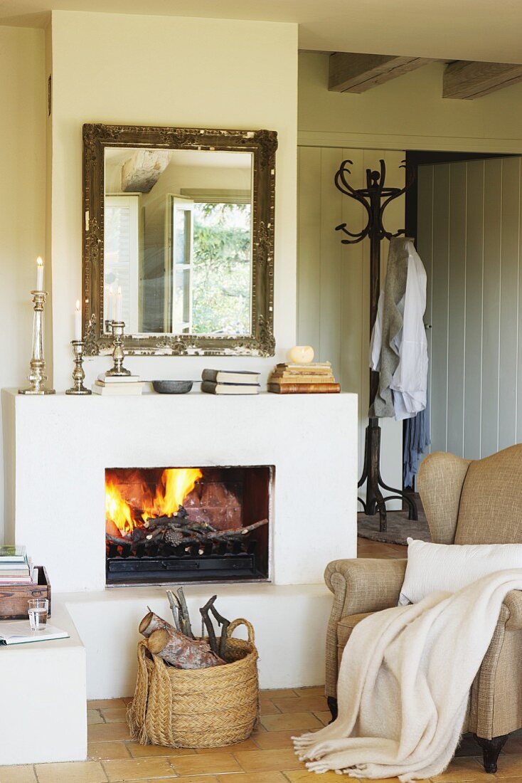 Wingback armchair next to basket of logs in front of open fire