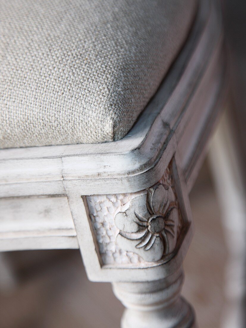 Detail eines Stuhlrahmens aus Holz mit geschnitztem Fuss und Polster mit Leinenüberzug