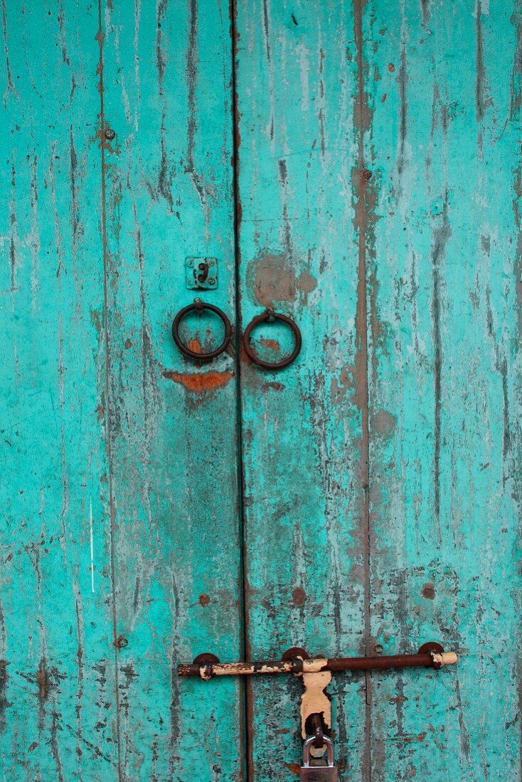 Verwitterte Holztür mit abblätternder hellblauer Farbe