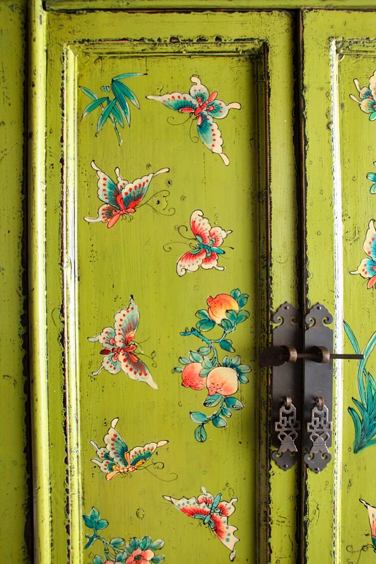 Vintage wardrobe with butterfly motifs painted on spring green background
