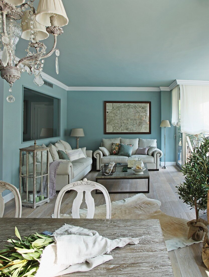 Bunch of twigs on table and white sofa set in lounge area against wall painted pale blue