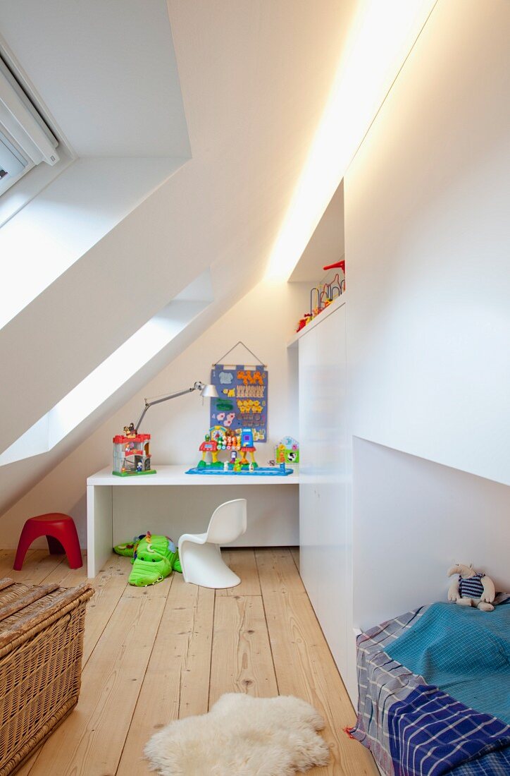 Original child's bedroom under steeply sloping ceiling; continuous recessed light strip above niches for desk and cubby bed in fitted cupboards