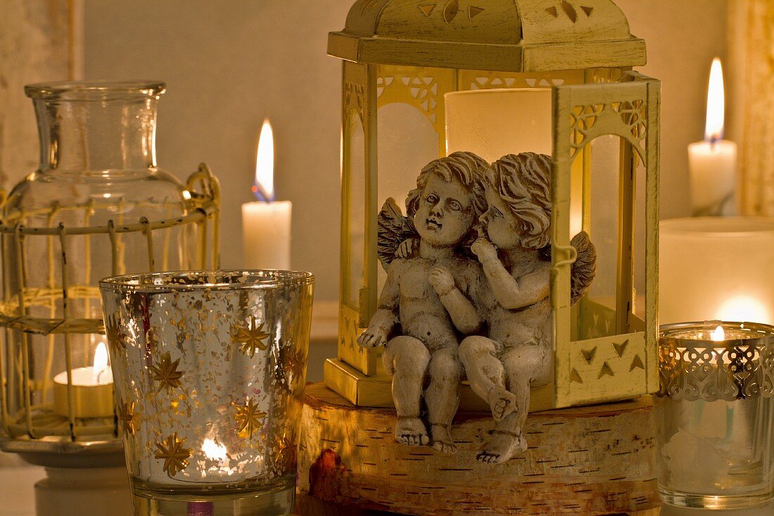 Engelfiguren in Laterne sitzend und Windlichter mit brennenden Kerzen