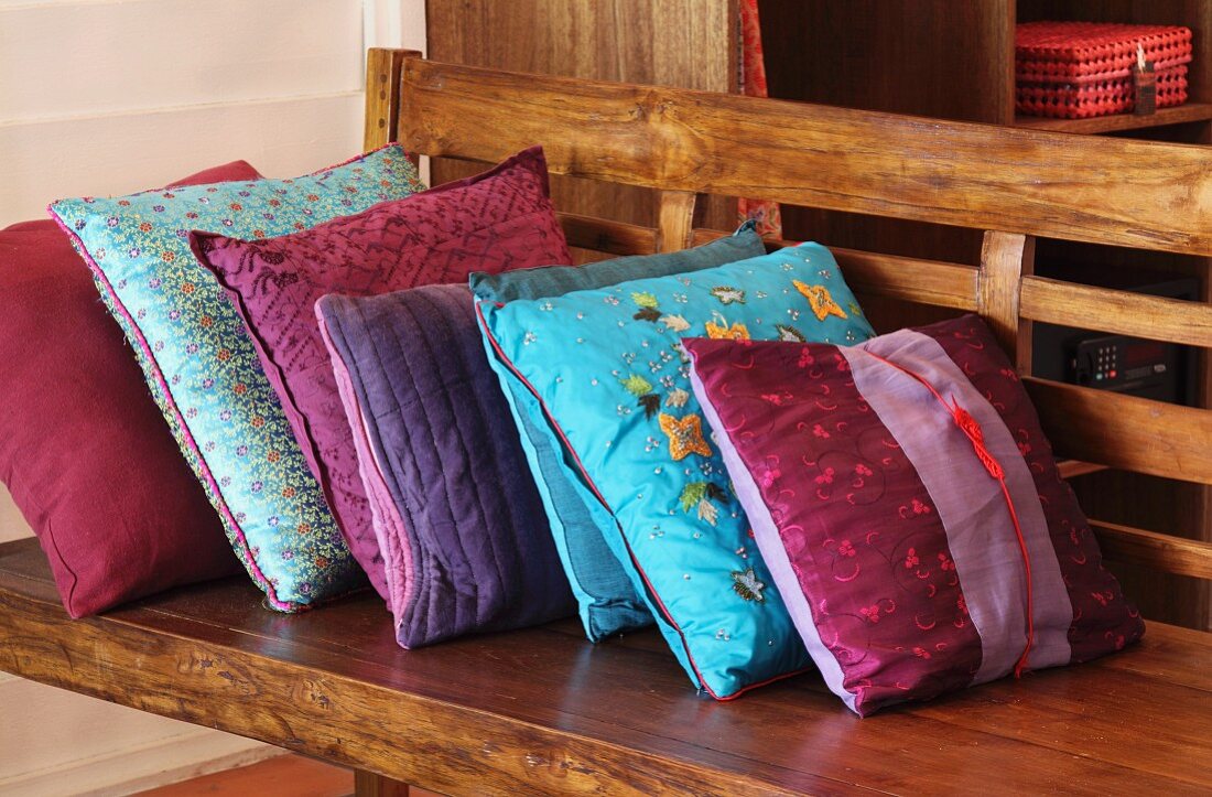 Cushions with variously patterned silk covers on wooden bench