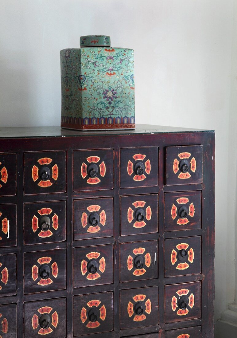 Oriental porcelain jar with lid on wooden chest of drawers painted with patterns