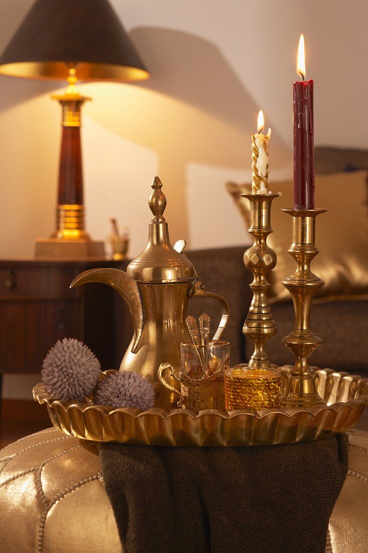 Arabisches Teeservice und goldene Kerzenleuchter auf Tablett im Wohnzimmer