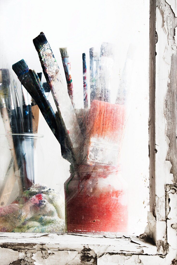 Benutzte Malerpinsel in Gläsernam Fenster