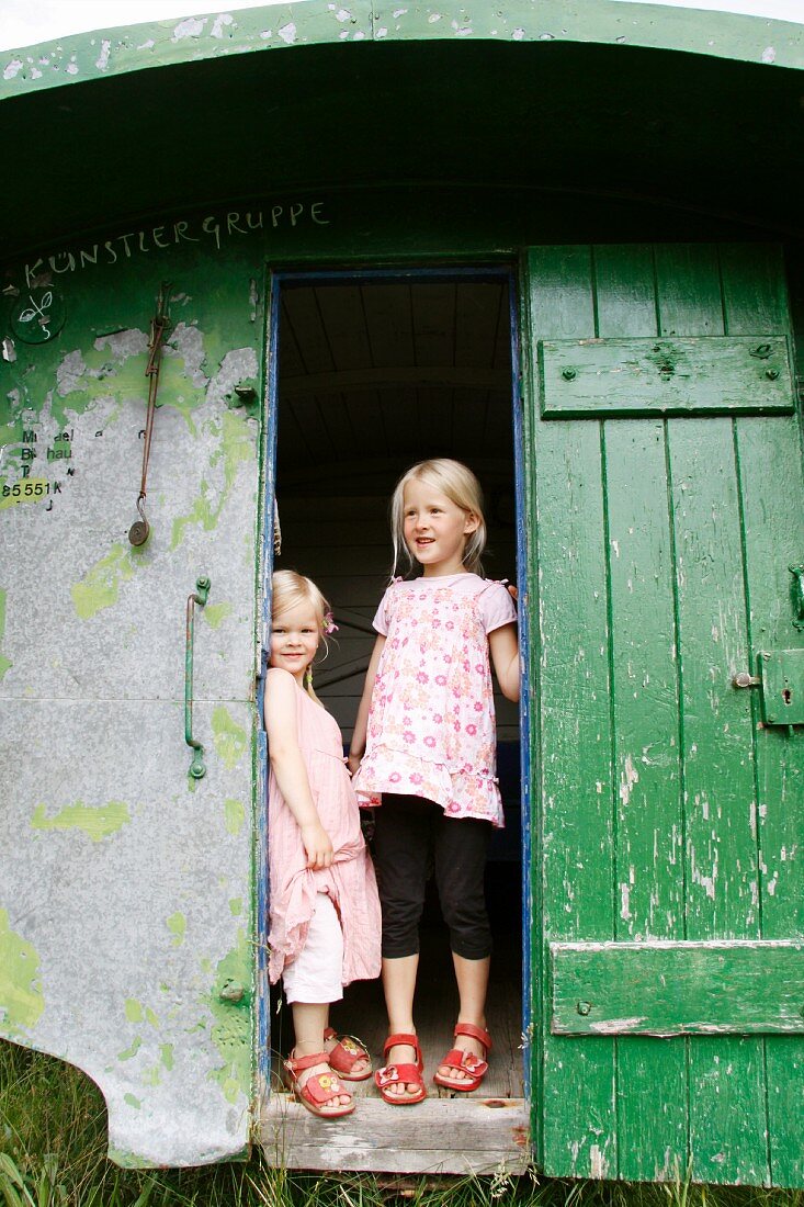 Zwei blonde Mädchen am Eingang eines Gartenhauses